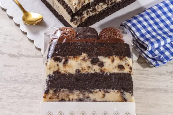 fatia de bolo de chocolate óreo com recheio e três brigadeiros em cima